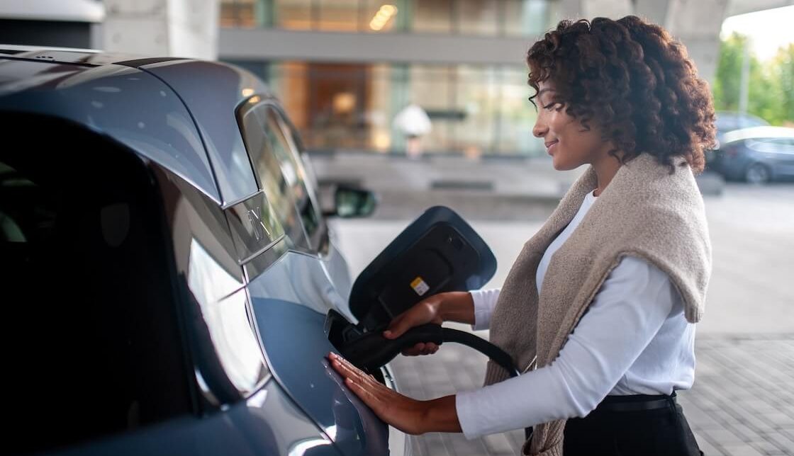 A woman plugging in her EV outside of an apartment building