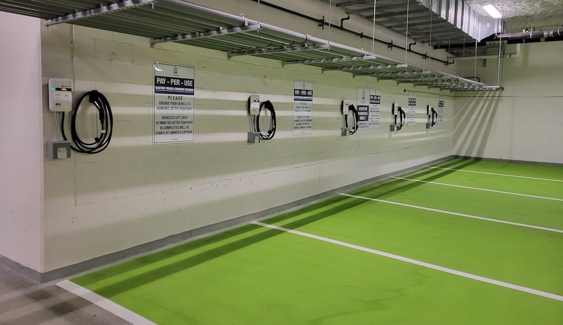 An image of several chargers in a row inside of a parking garage